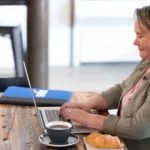 A female healthcare professional at her desk at night, studying on a laptop, demonstrating the flexibility of an online master's in healthcare administration